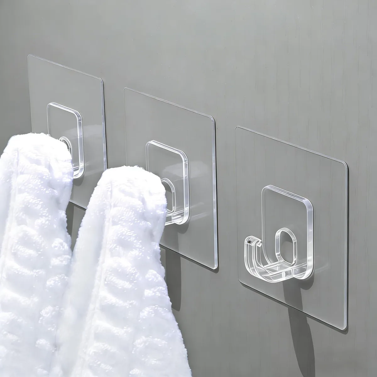 Clear adhesive hooks in a pack of twelve, transparent PVC finish, smooth low-profile design