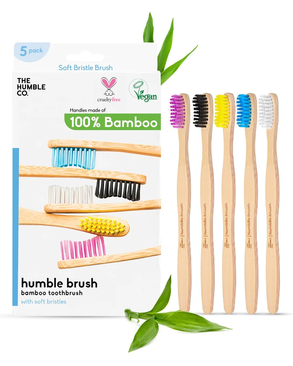 Five light bamboo toothbrushes with white soft bristles lying side by side