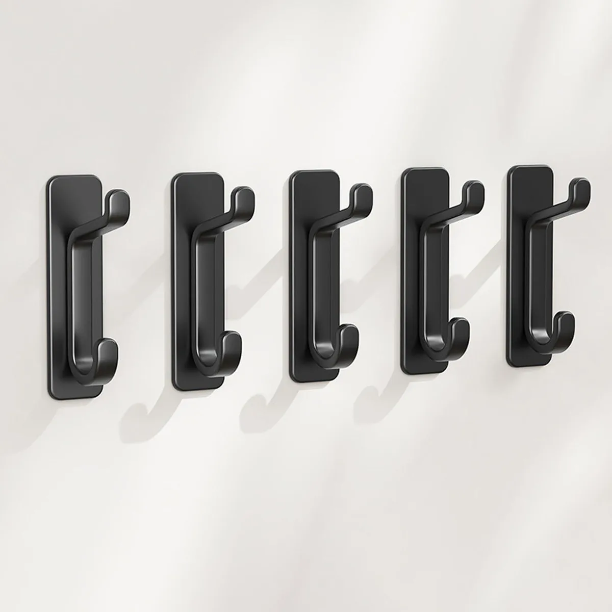 Four black adhesive dual hooks on a white background
