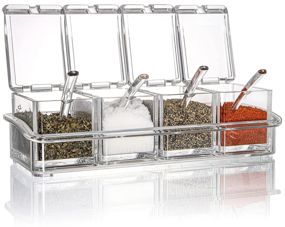 Four red acrylic spice jars with spoons on a clear tray