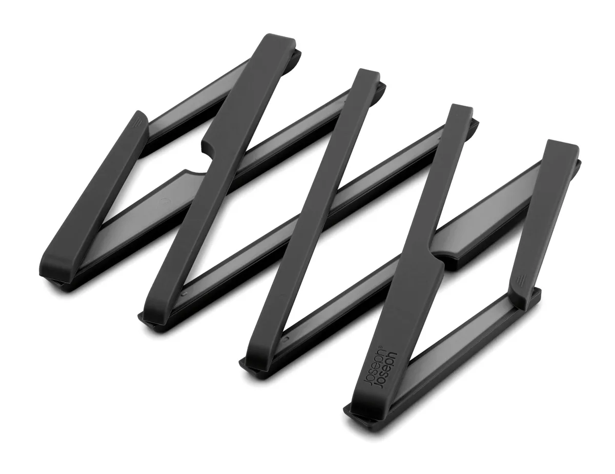 Black expandable silicone trivet folded flat on surface