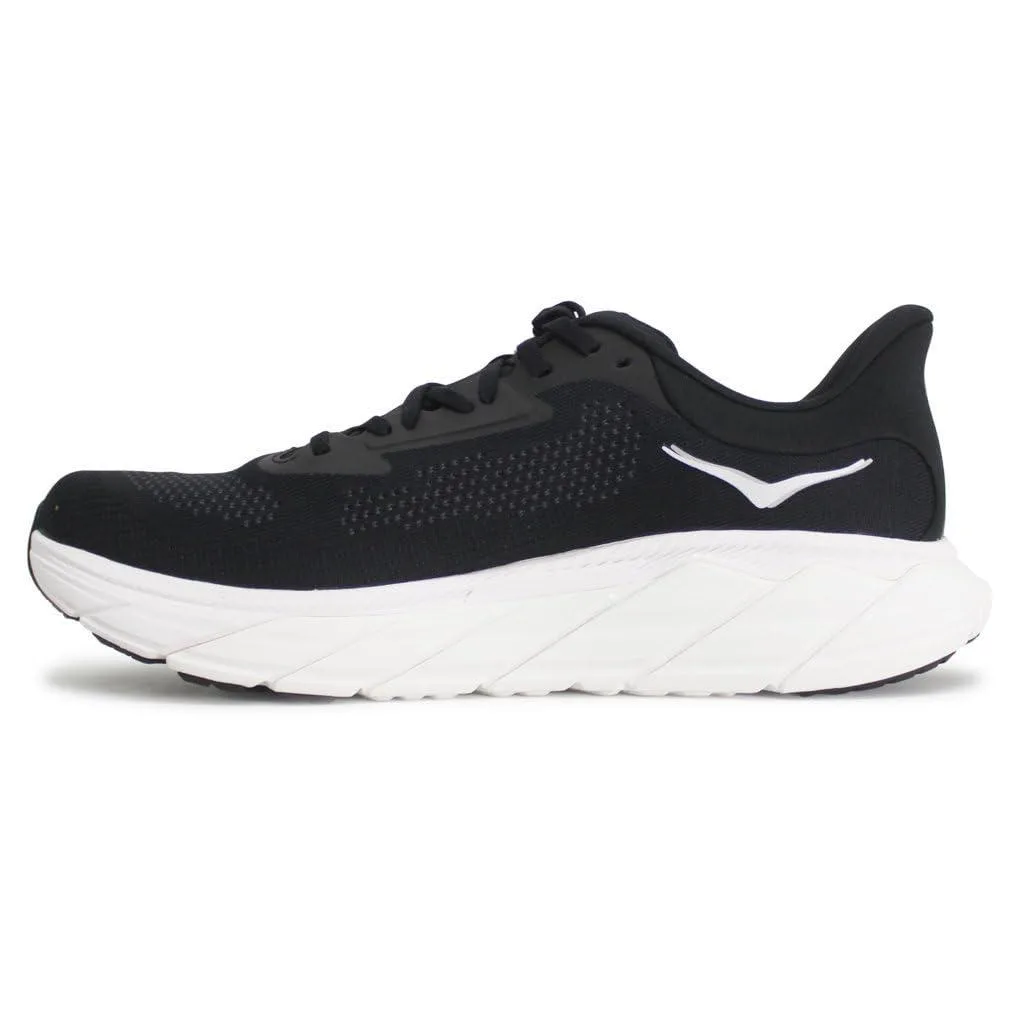 HOKA Arahi 7 sneaker in black and white, low-profile mesh upper with structured overlays, thick cushioned midsole, rubber outsole