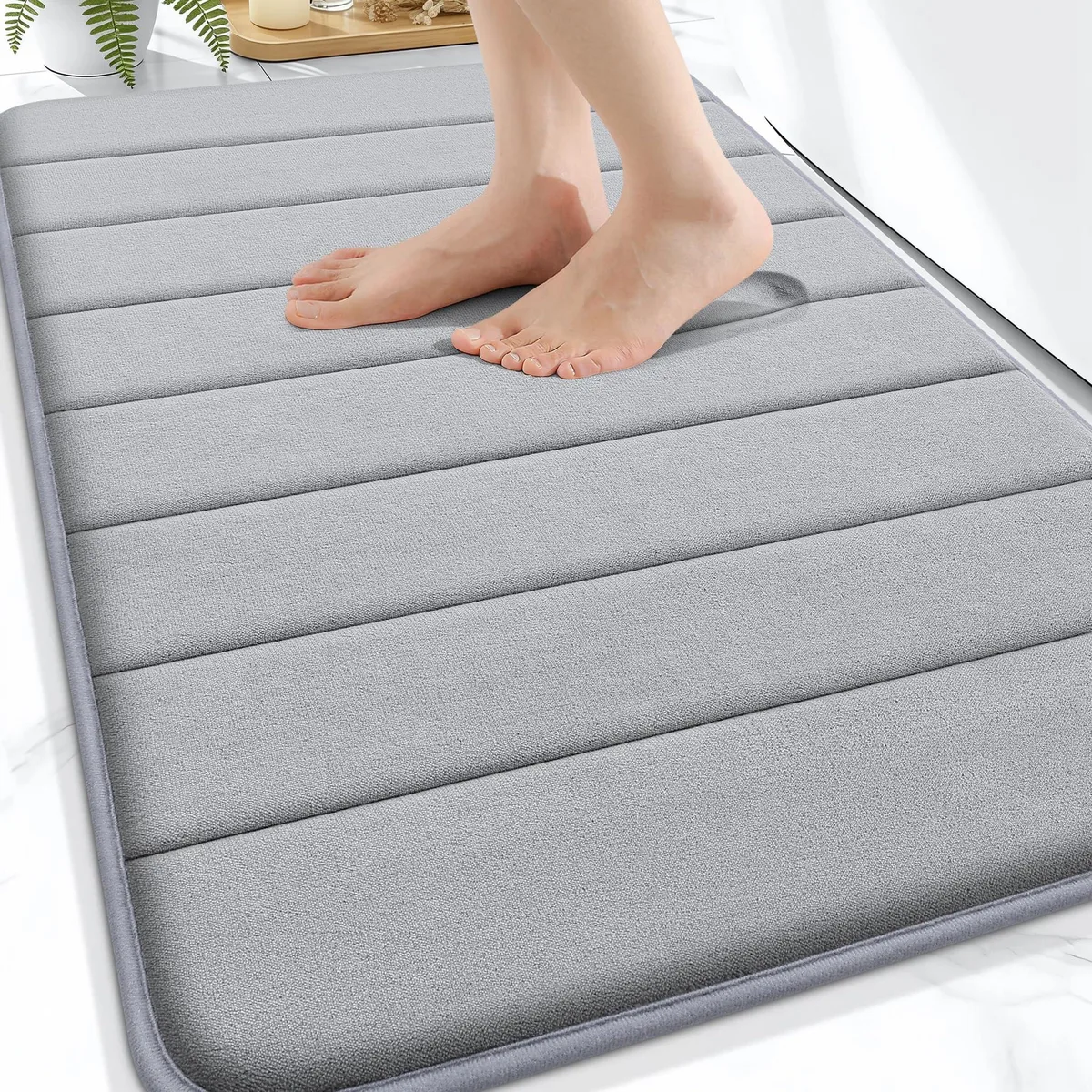 Grey rectangular bath mat with diamond-patterned PVC backing visible on folded edge