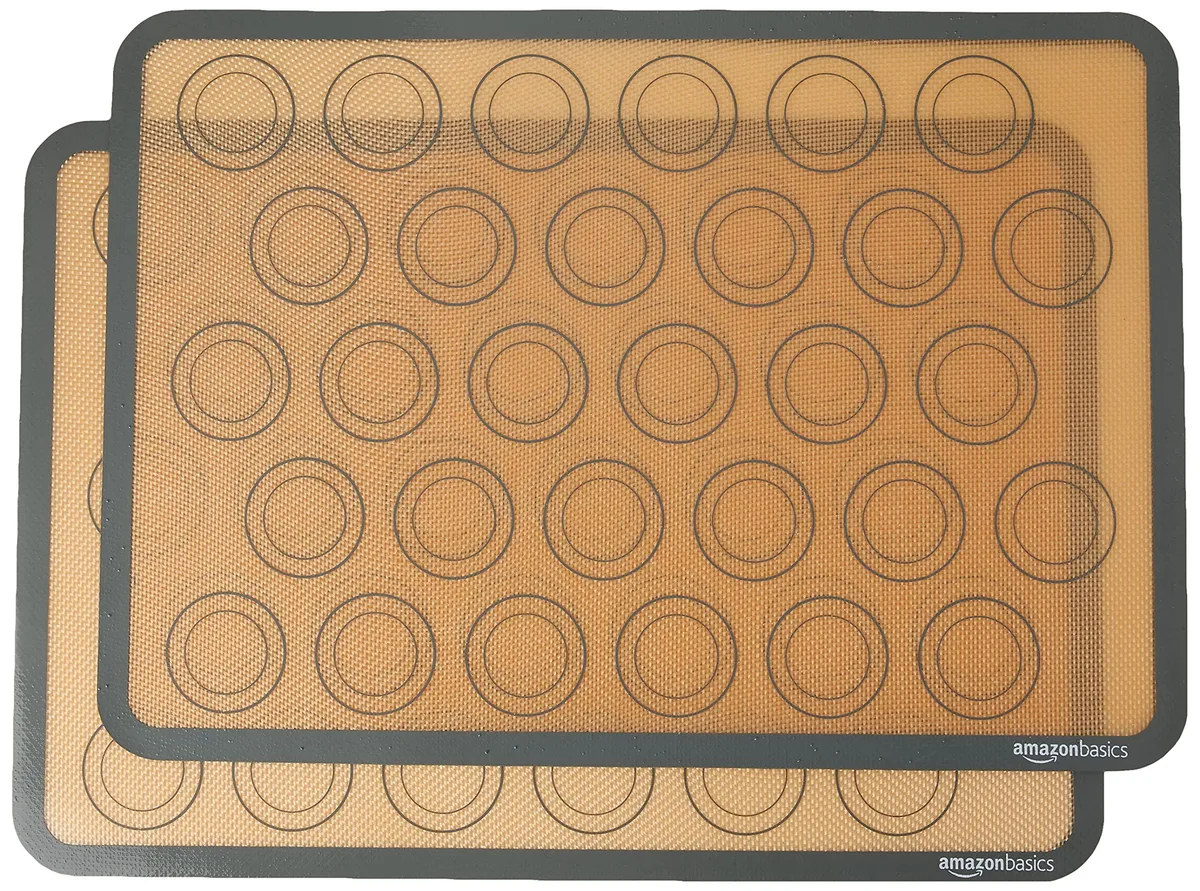Two beige-gray silicone baking mats with printed circles for 30 macarons each