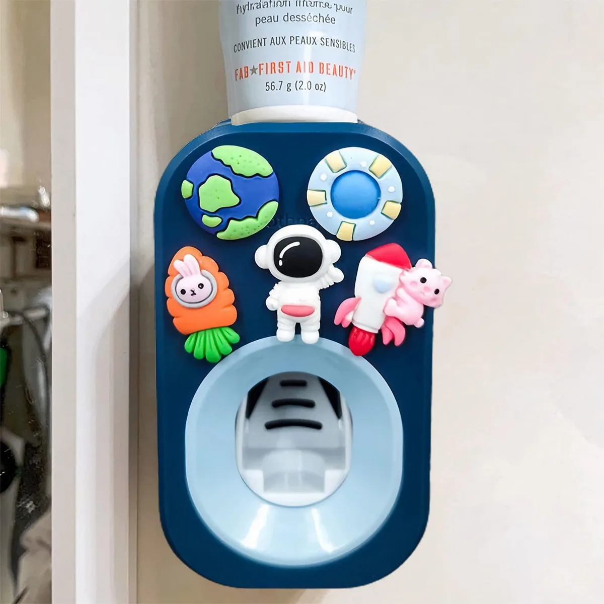 White astronaut-shaped automatic toothpaste dispenser, wall-mounted with adhesive sticker
