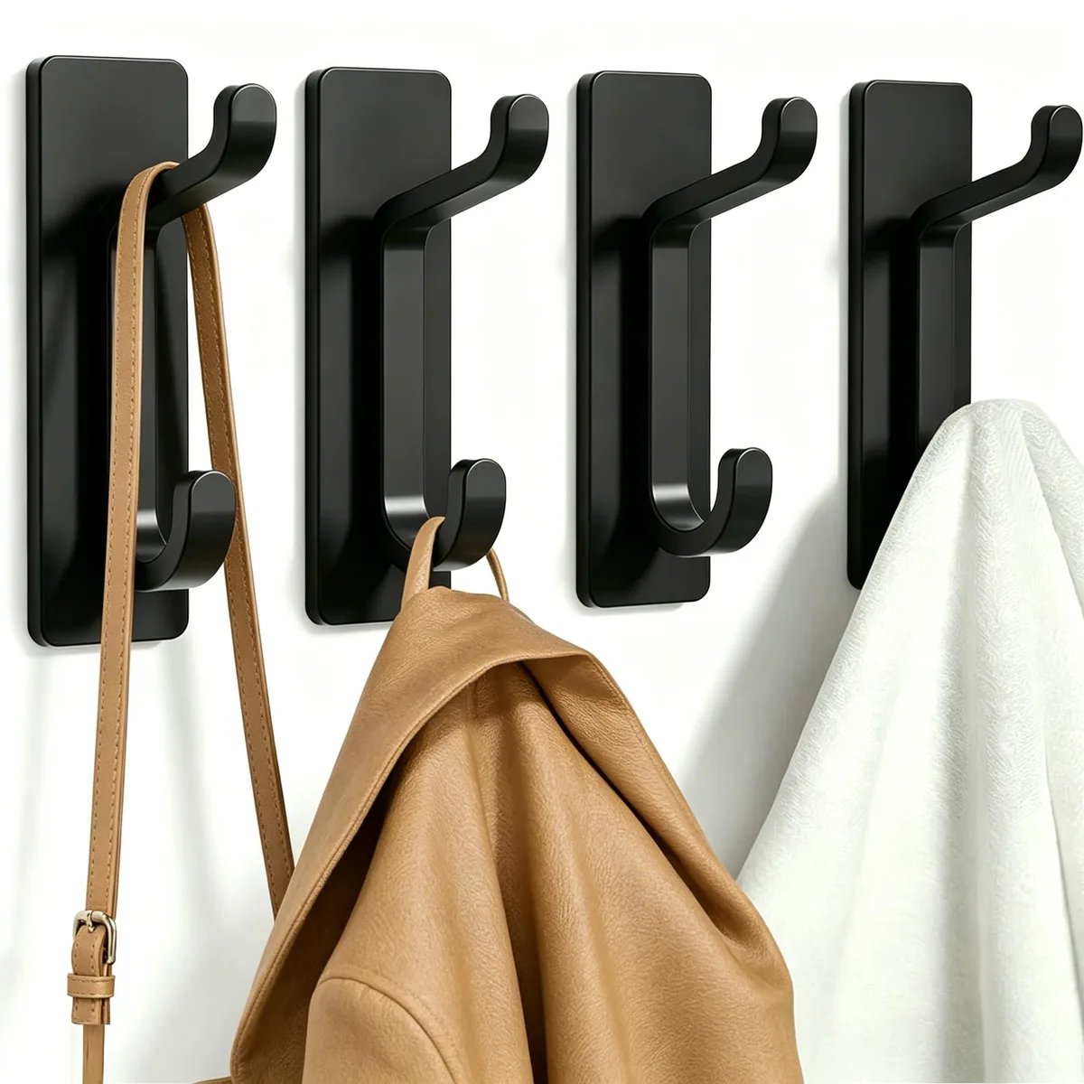 Four black polished metal adhesive wall hooks in a row