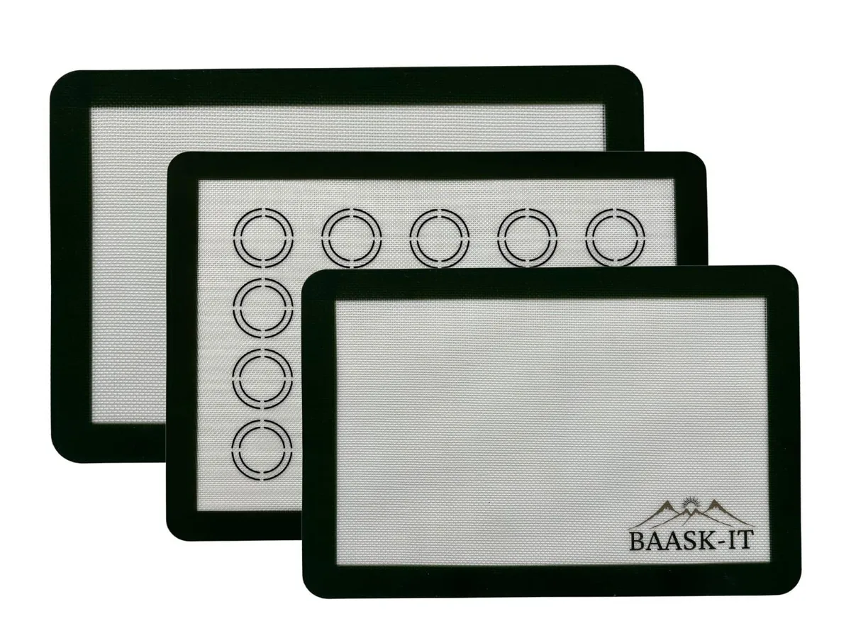 Three silicone baking mats, two large with dark green borders, one with macaron circles