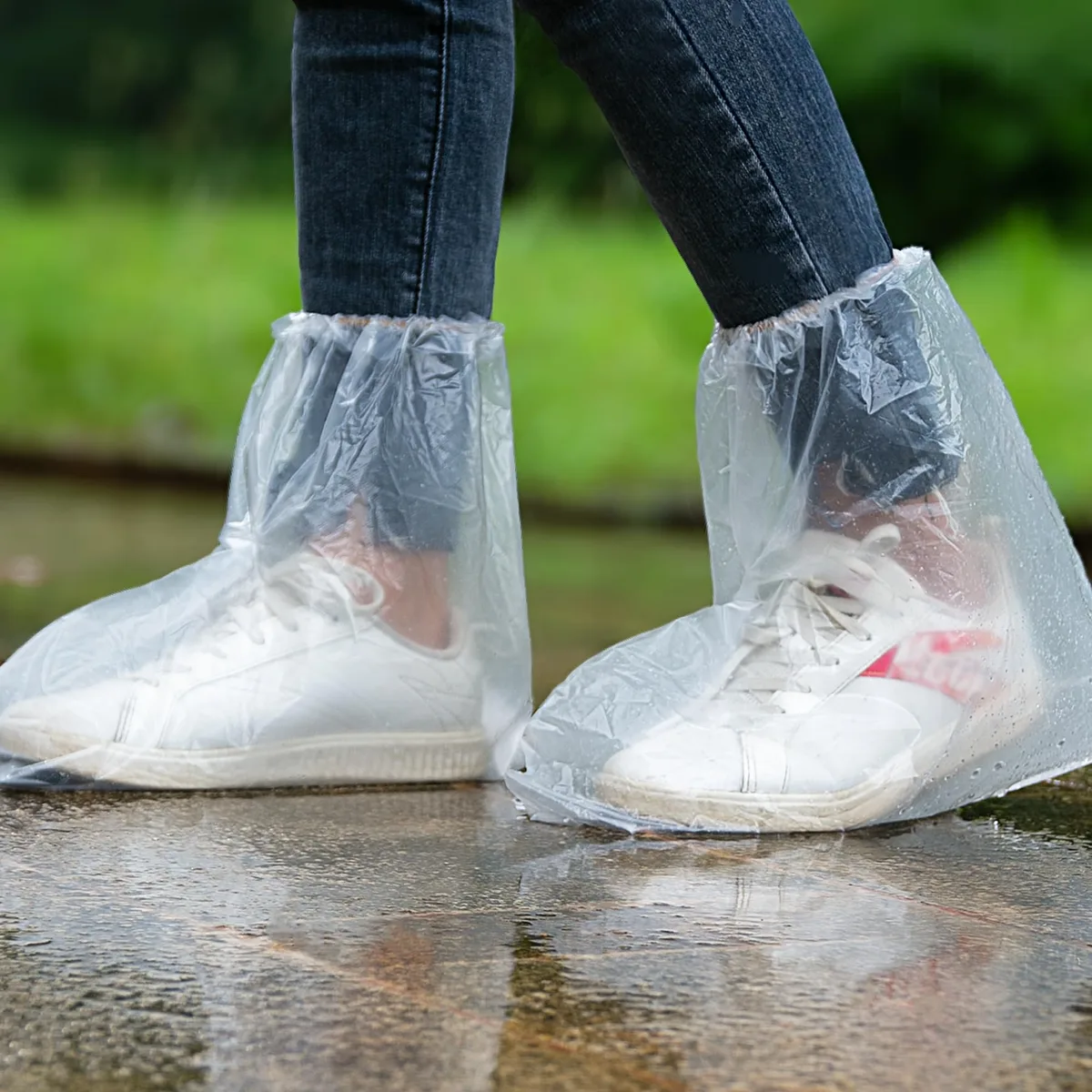 Clear disposable plastic shoe covers in medium size, ten pairs shown flat with elastic openings and textured soles