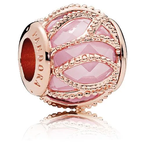 A silver charm with pink stone and twisted rose-gold metal strands