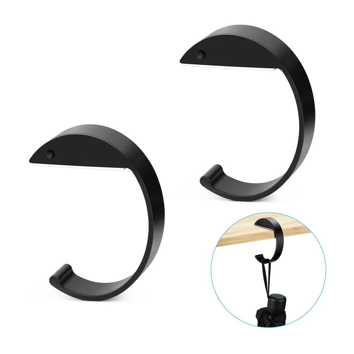 Two black C-shaped metal purse hooks on a flat surface