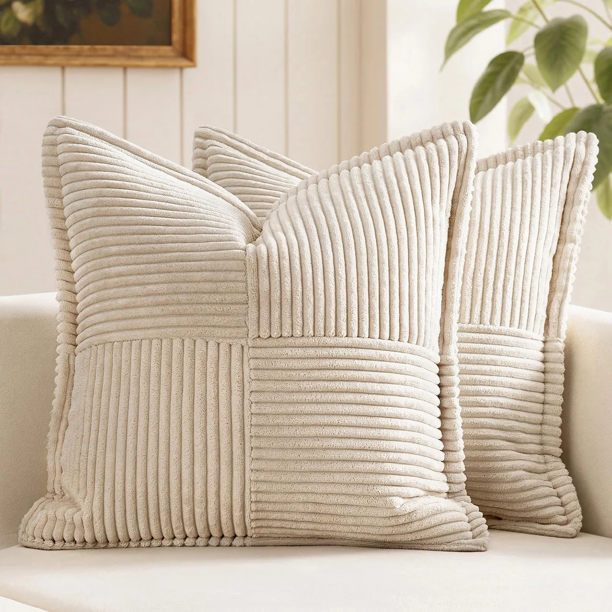 Two beige square corduroy pillow covers with striped patchwork design and piping edges