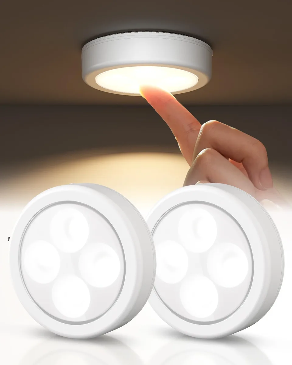 Two small white puck lights with clear prismatic lenses and adhesive backing