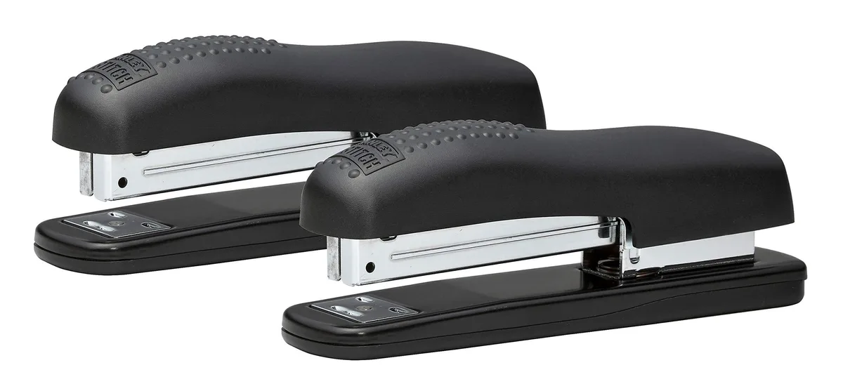 Two black ergonomic desktop staplers with raised grips and metal bodies