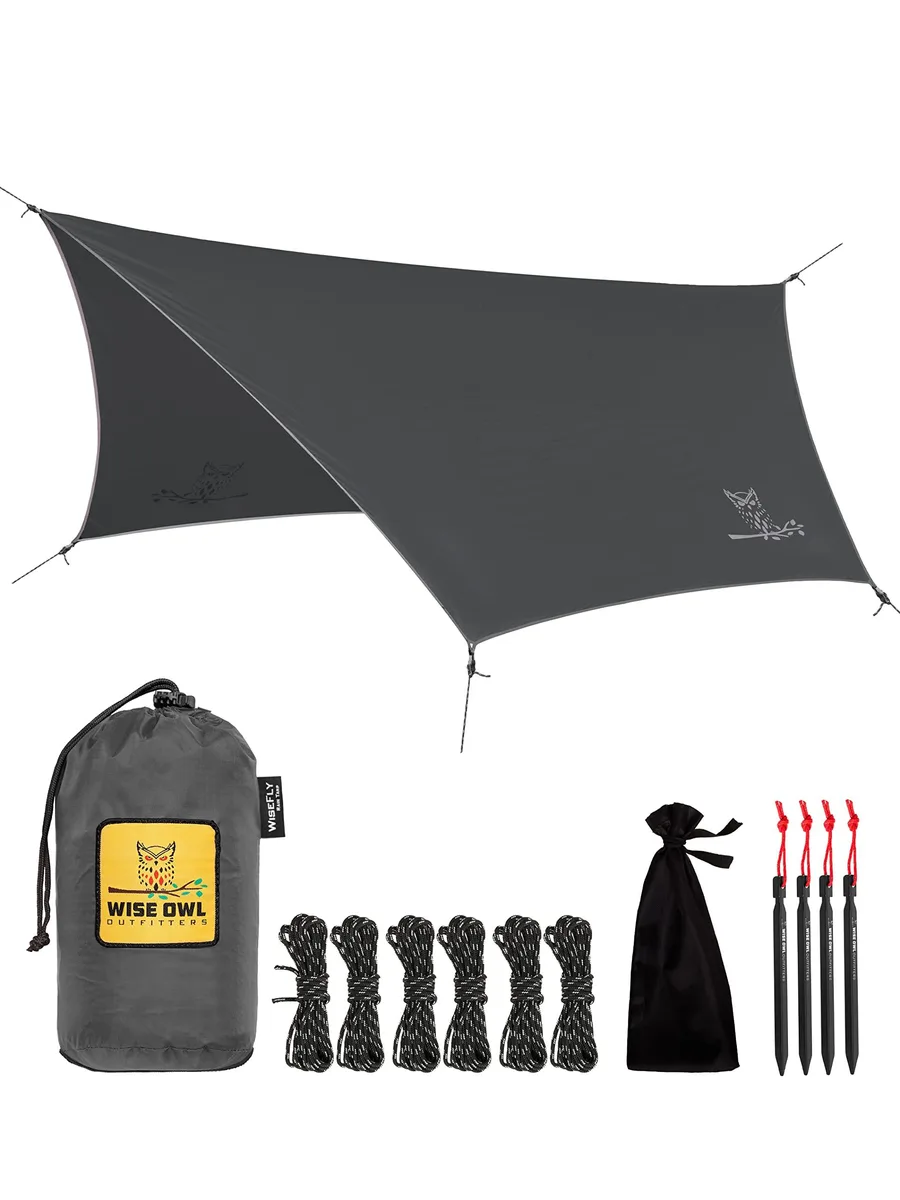 Grey rectangular tarp with reinforced corners and guy lines, packed in a drawstring bag with aluminium stakes