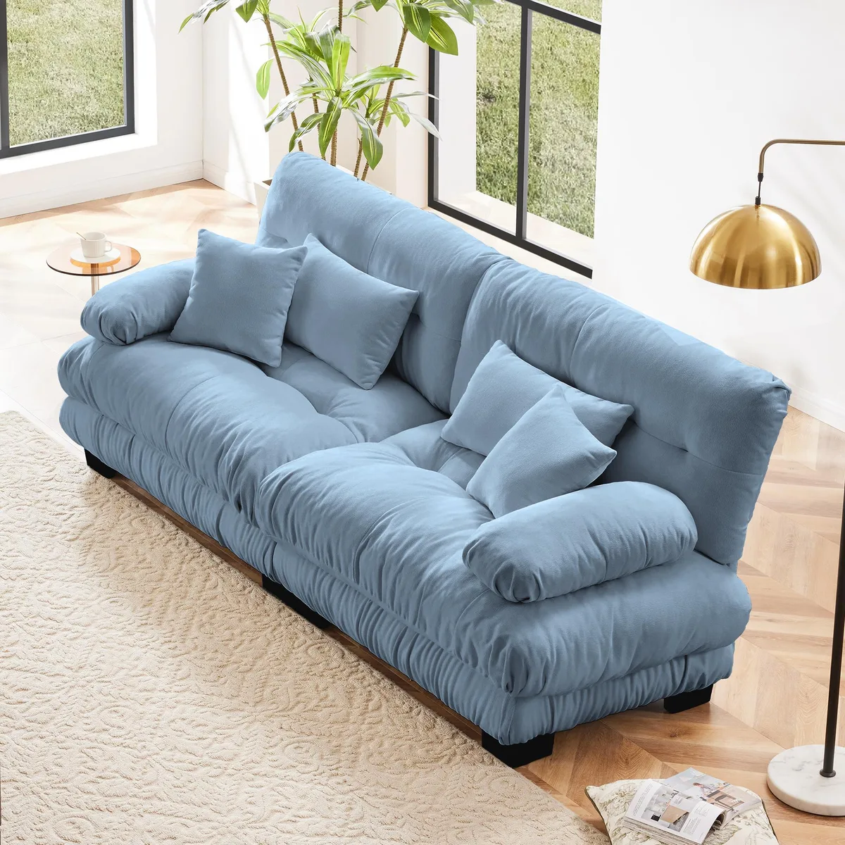 Blue chenille two-seater sofa with rounded bolster armrests and four pillows