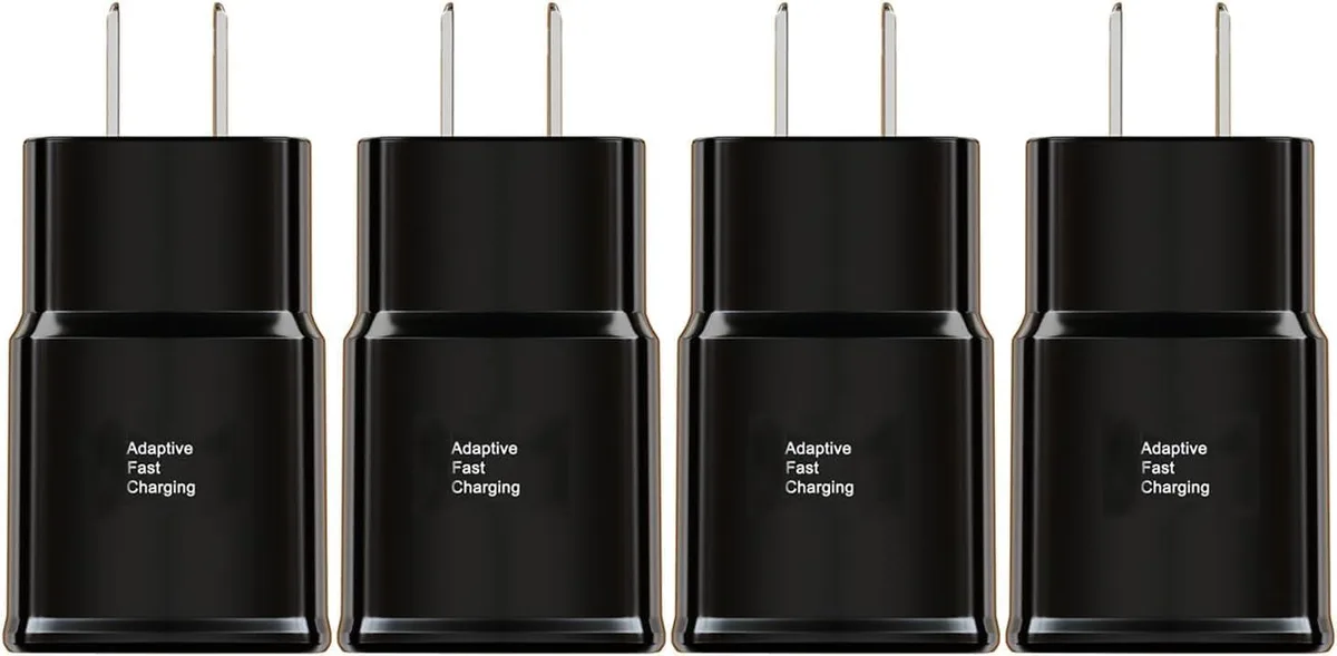 Four compact white wall chargers with USB ports on a light surface