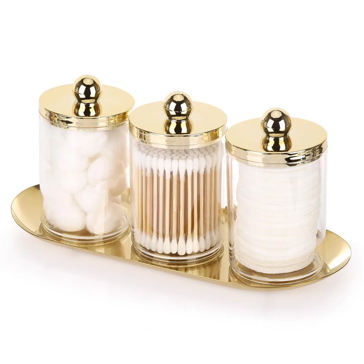 Three clear plastic canisters with gold lids on a gold iron tray