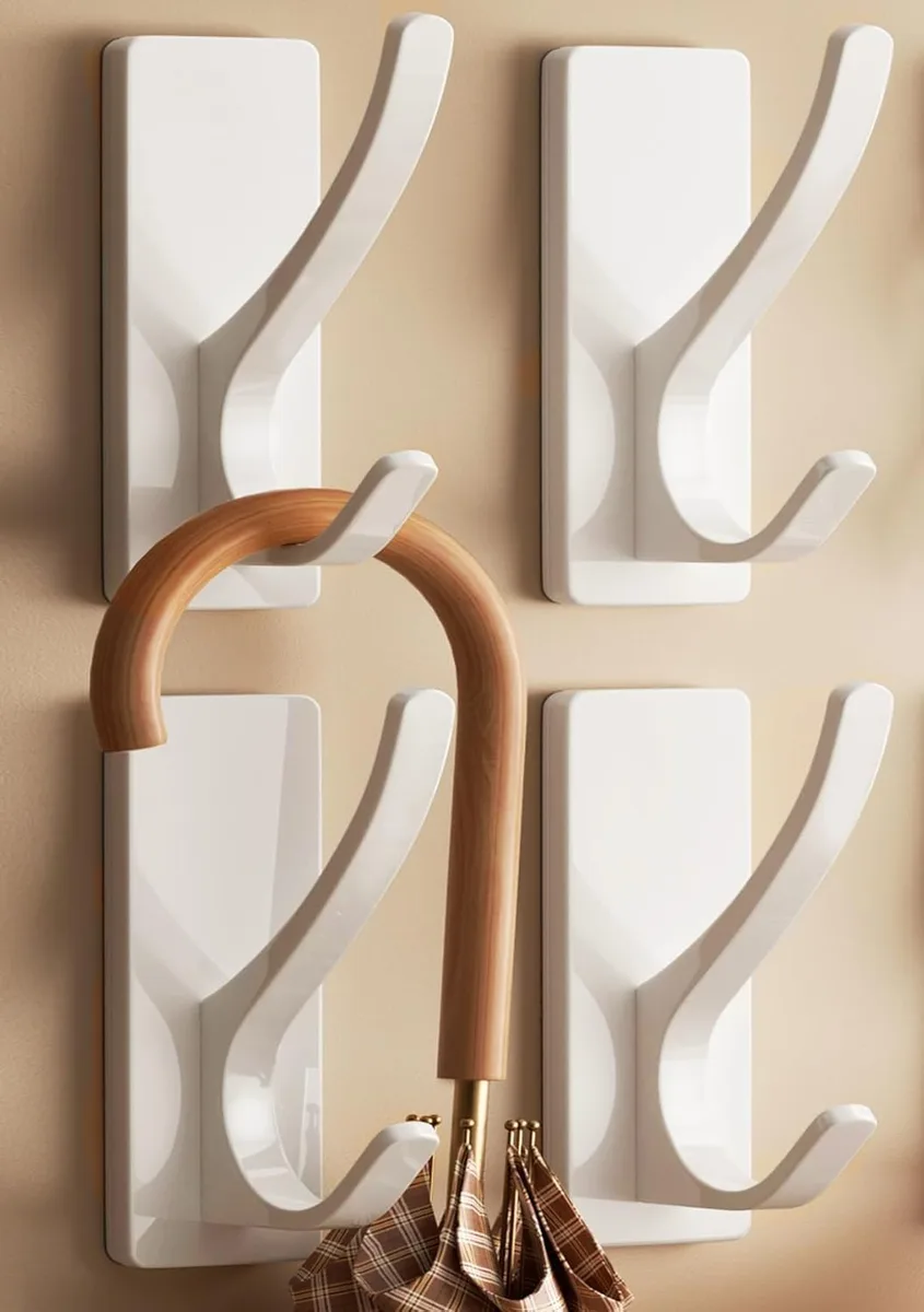 Four white powder-coated metal double hooks with adhesive backing