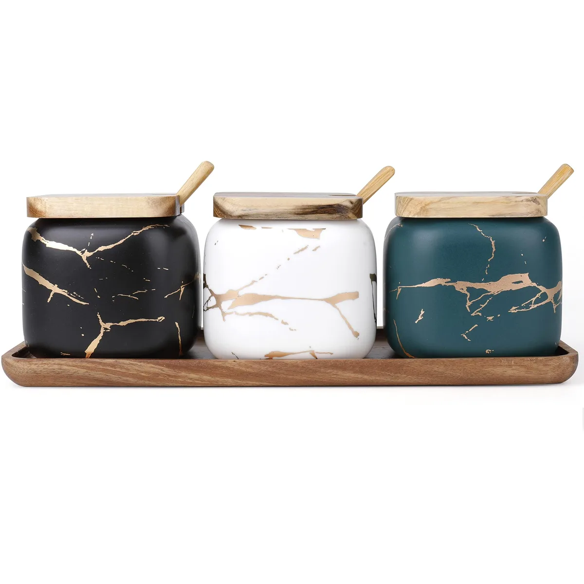 Three black ceramic jars with lids and spoons on a bamboo tray