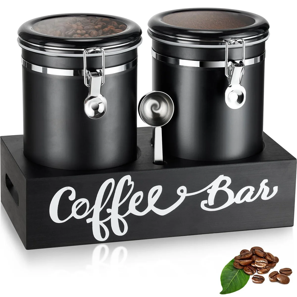 Two black stainless steel canisters on a wooden shelf with a silver scoop