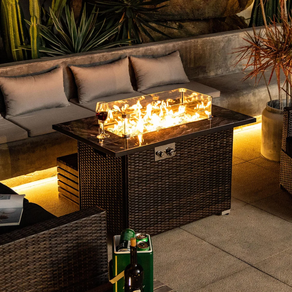 Rectangular espresso fire pit table with gray marble tile top and wicker base, glass windscreen visible