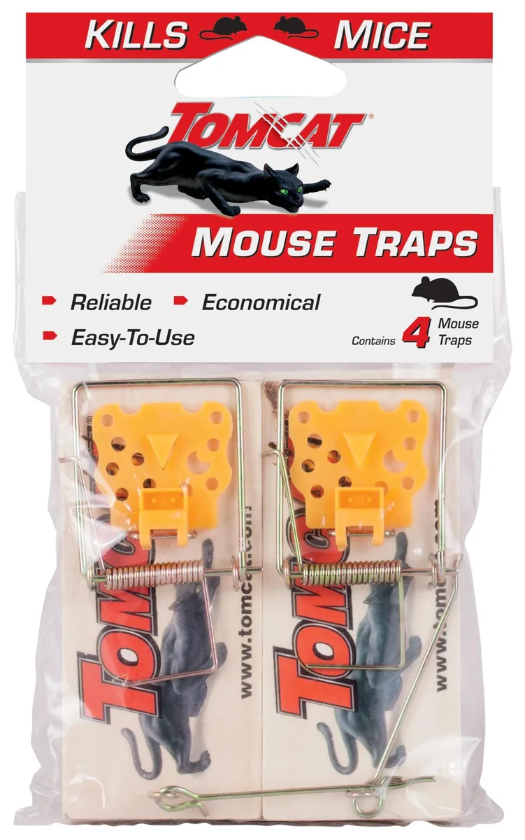 Four light wooden mouse traps with metal U-shaped bars and triggers on a plain surface