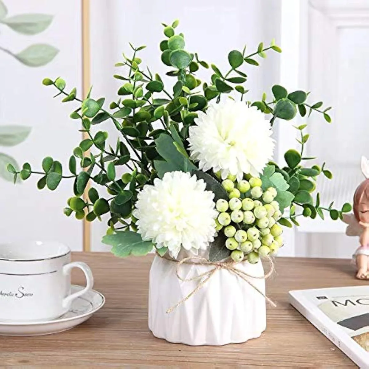 White ceramic vase holding pink hydrangea eucalyptus and berry stems arranged in a compact bouquet