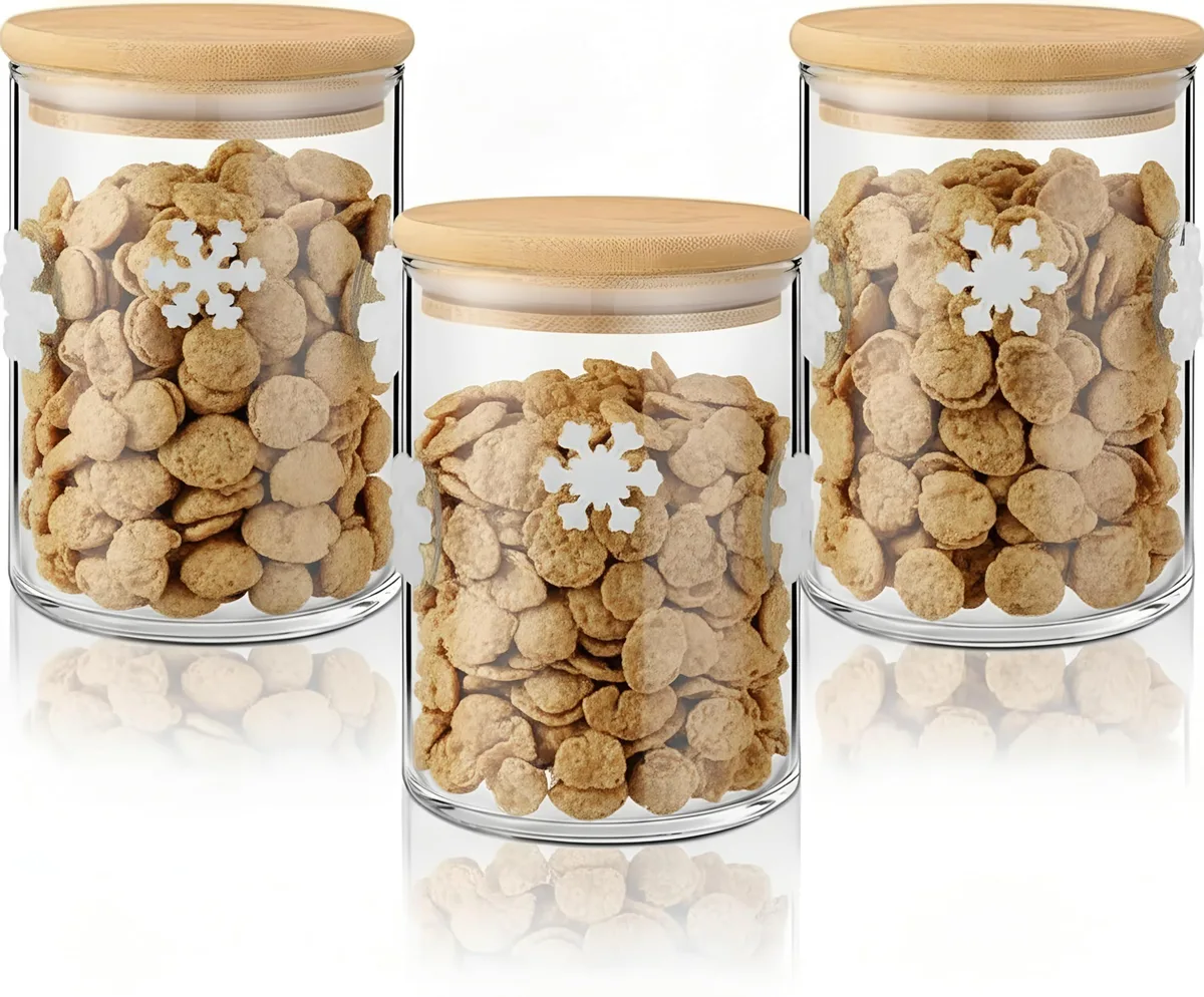 Three white glass jars with snowflake prints and bamboo lids