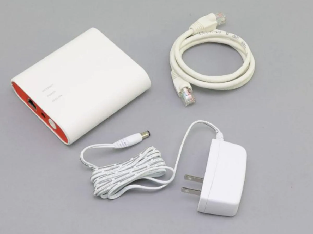 Small white rectangular gateway with Ethernet cable and power adapter