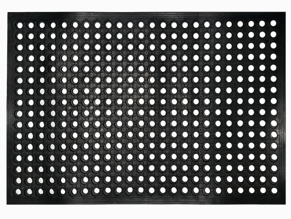 Black rectangular rubber mat with raised polka-dot pattern and drainage holes, 35 by 23 inches