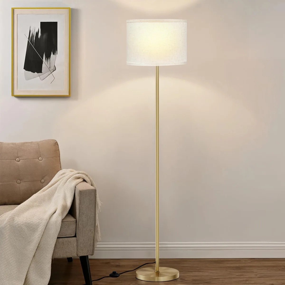 Tall floor lamp with beige fabric shade and gold pole