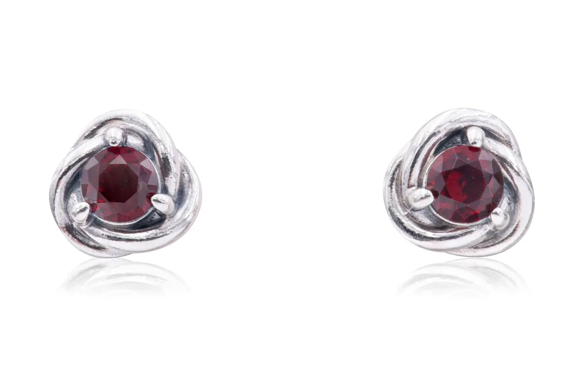 Pair of silver-tone stud earrings with infinity braid circles and red crystals at centres