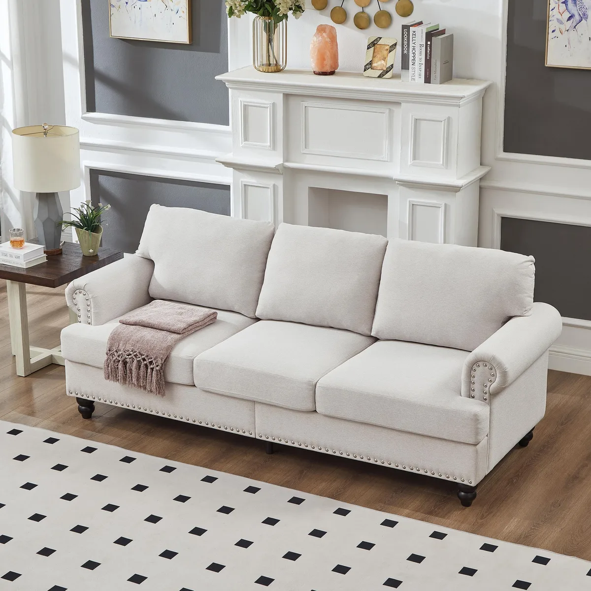 Beige three-seater sofa with nailhead trim and wooden legs
