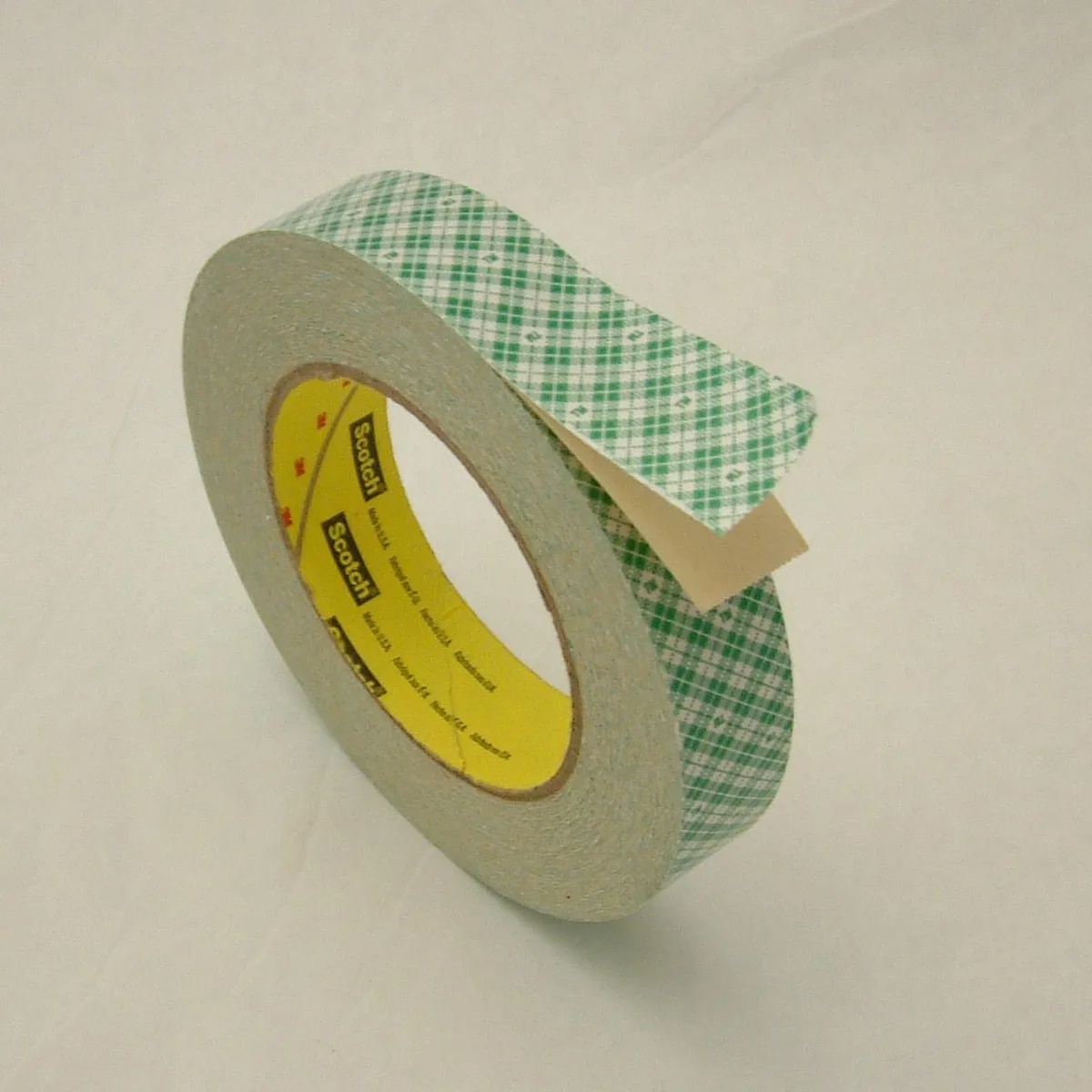Off-white double-sided paper tape roll on green plaid liner