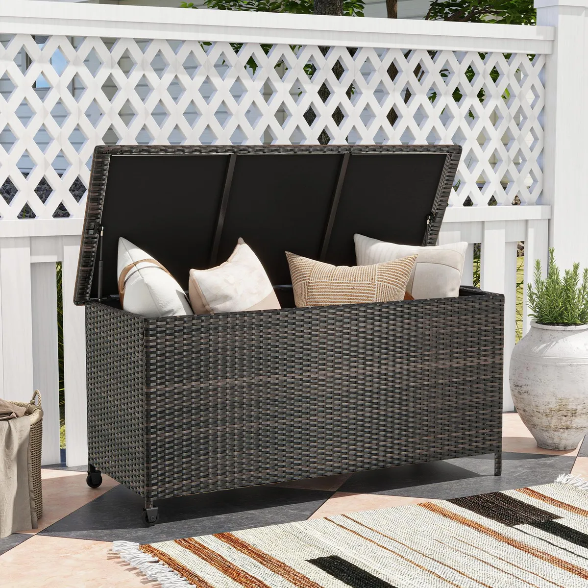 Brown rectangular patio storage box with rattan texture, metal frame, universal wheels and gas-strut lid