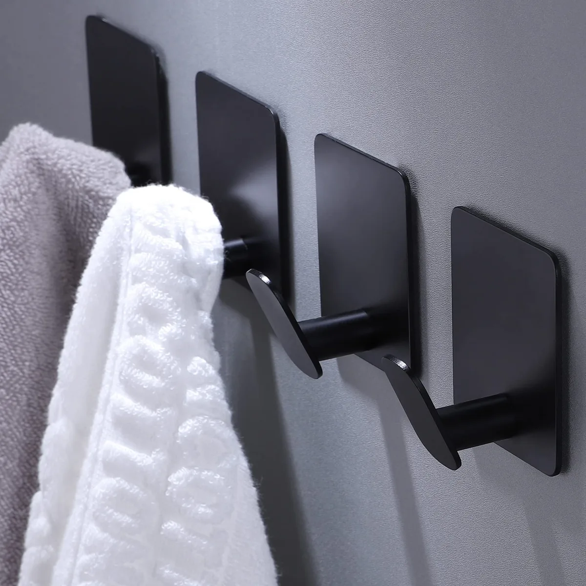 Four matte black square adhesive hooks with rounded corners