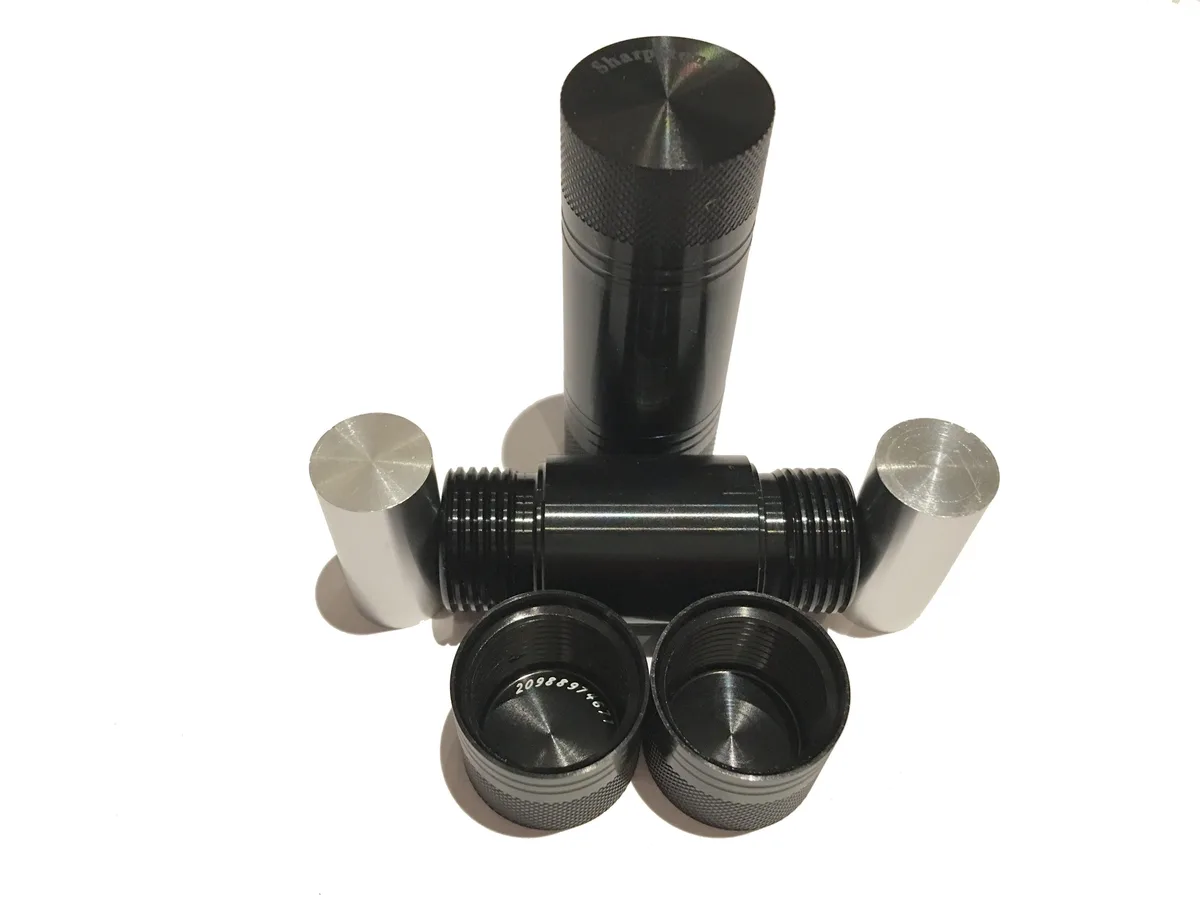 Set of five small black cylindrical presses with silver pins, each about three-quarters of an inch wide