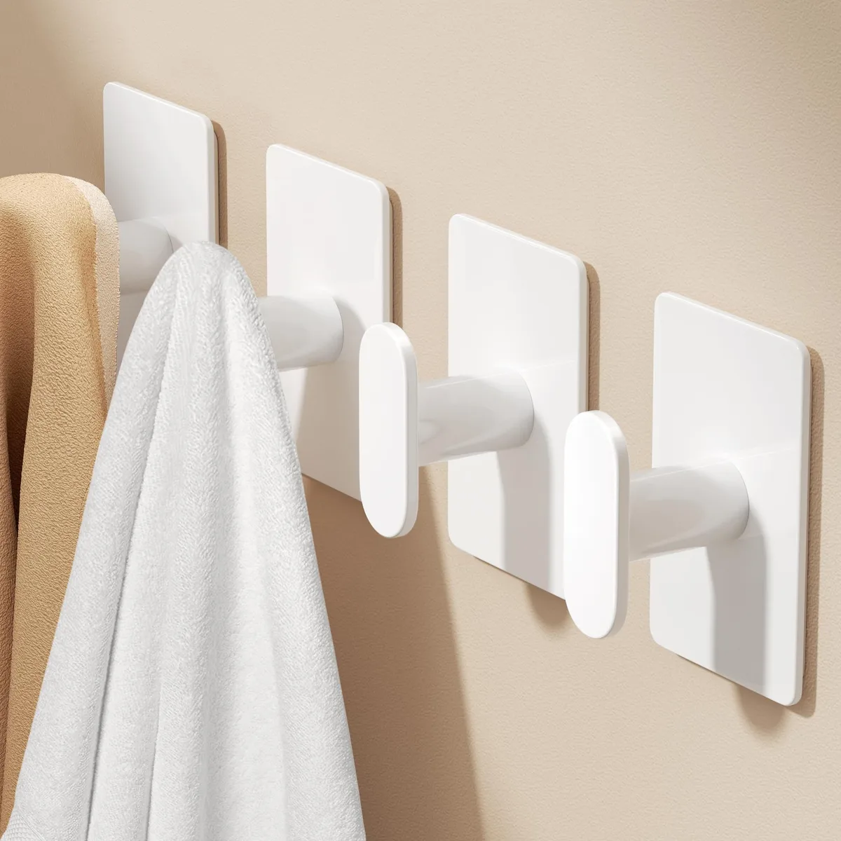 Four white adhesive wall hooks with smooth minimalist design