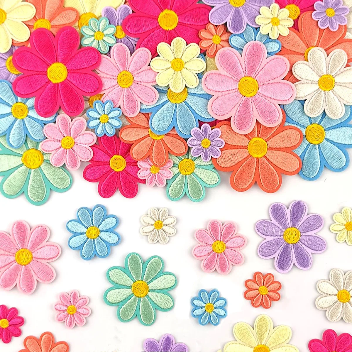 A spread of multicolour embroidered daisy patches in four sizes on polyester fabric