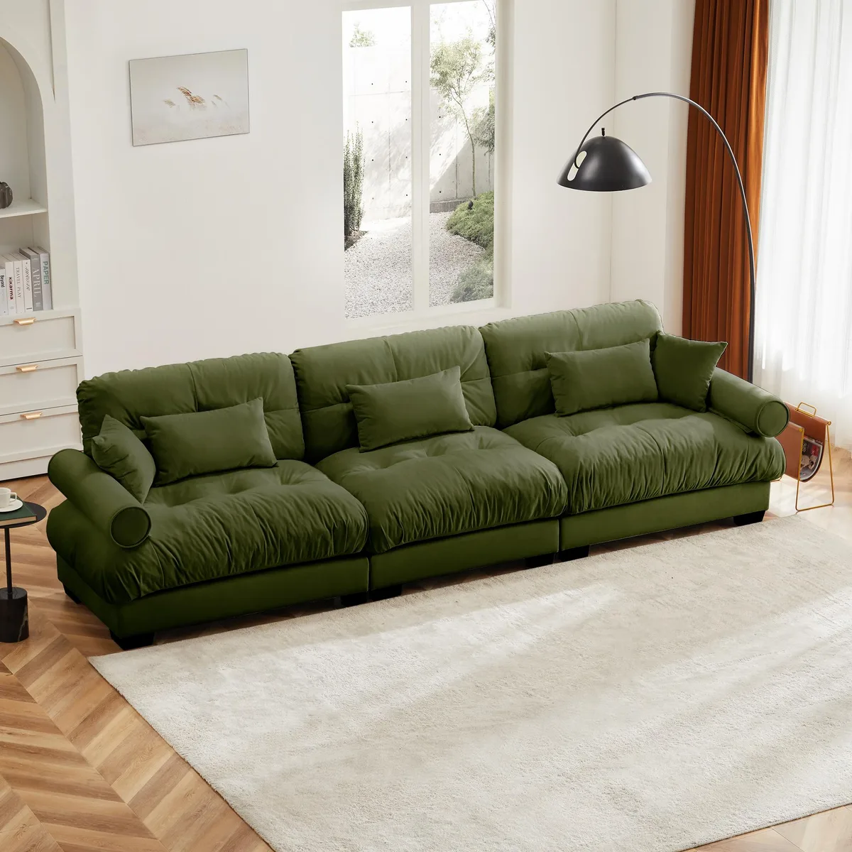 Olive green velvet three-seater sofa with bolster armrests and scatter cushions