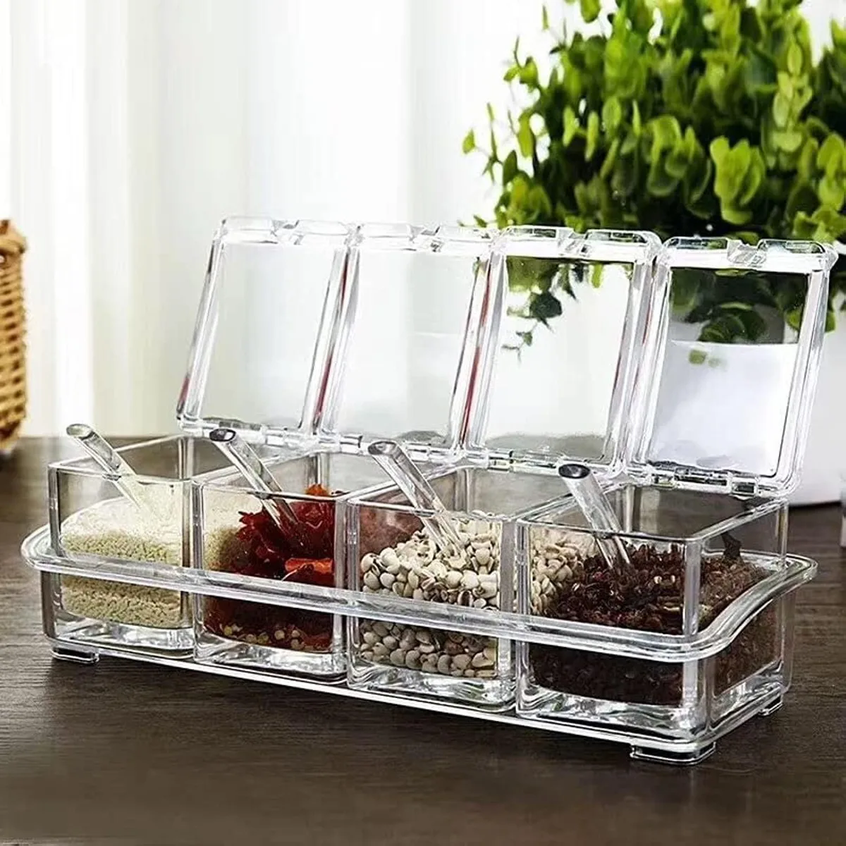 Clear acrylic tray holding four square spice jars with lids and spoons