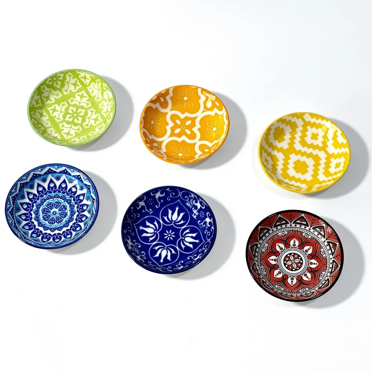 Six small round ceramic bowls in brown and red floral patterns, stacked together