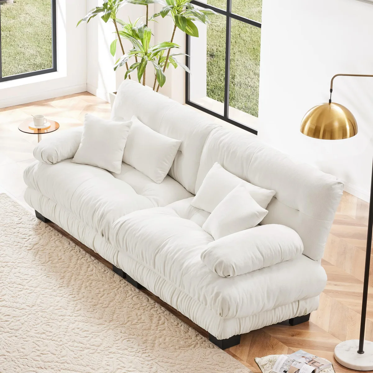 White chenille two-seater sofa with rounded bolster armrests and four included pillows