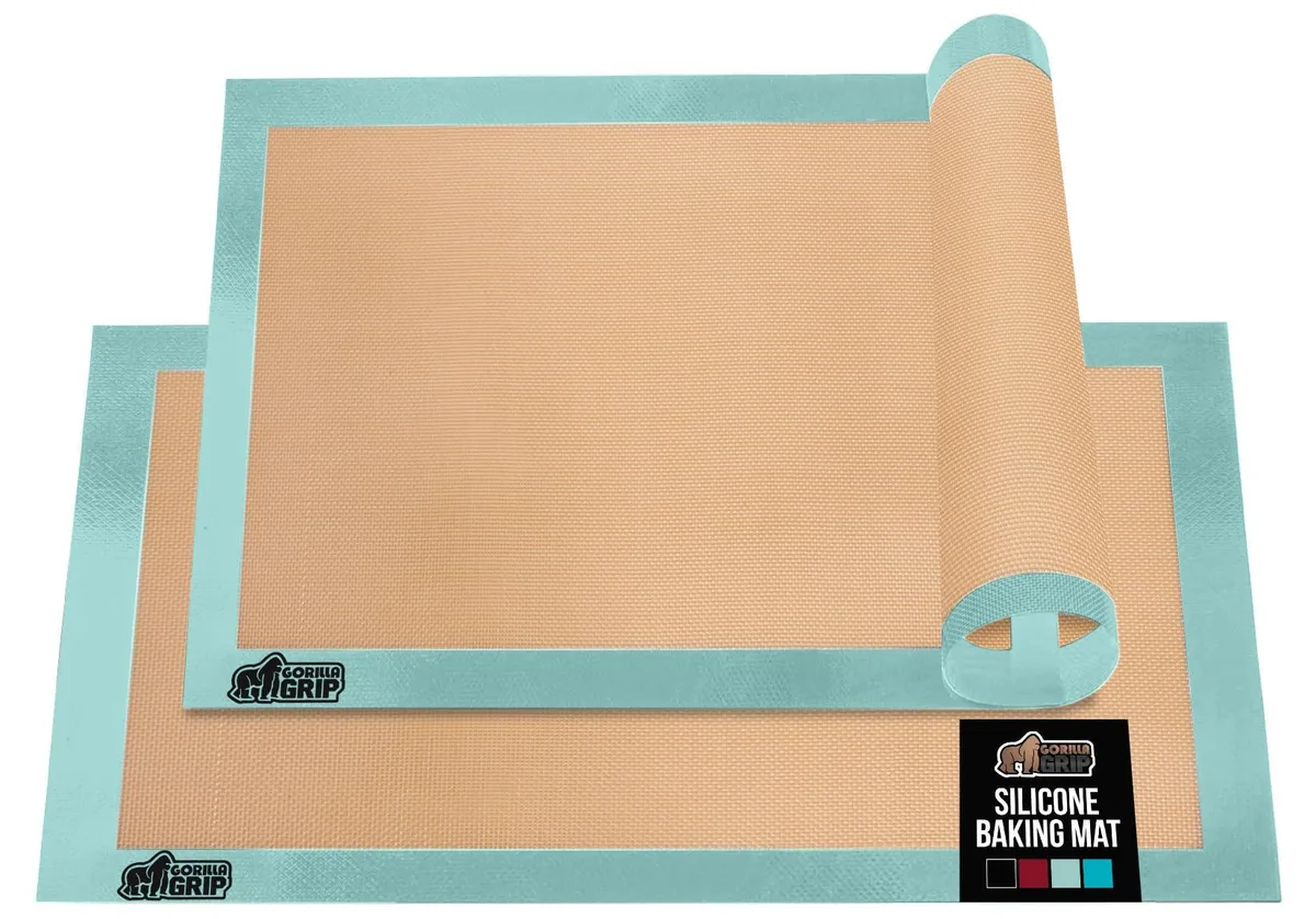 Two mint-green rectangular silicone baking mats on a half-sheet pan