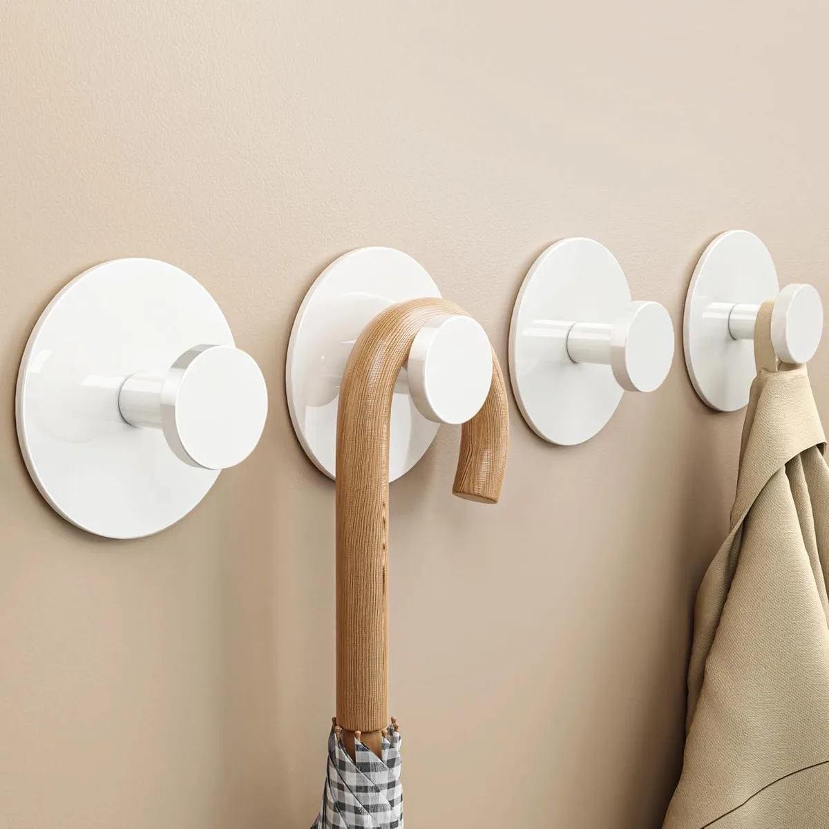 Four white stainless steel adhesive wall hooks on a surface