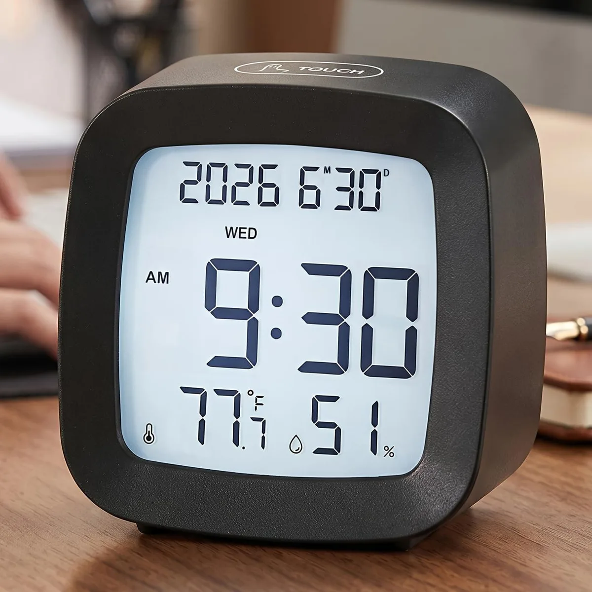 Black rectangular digital alarm clock with tilted LCD display showing time date temperature humidity, compact 3.1 by 1.5 by 3.0 inches