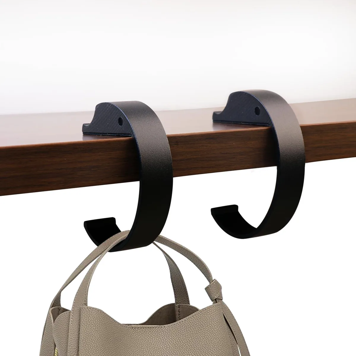 Two black C-shaped metal purse hooks with non-slip pads