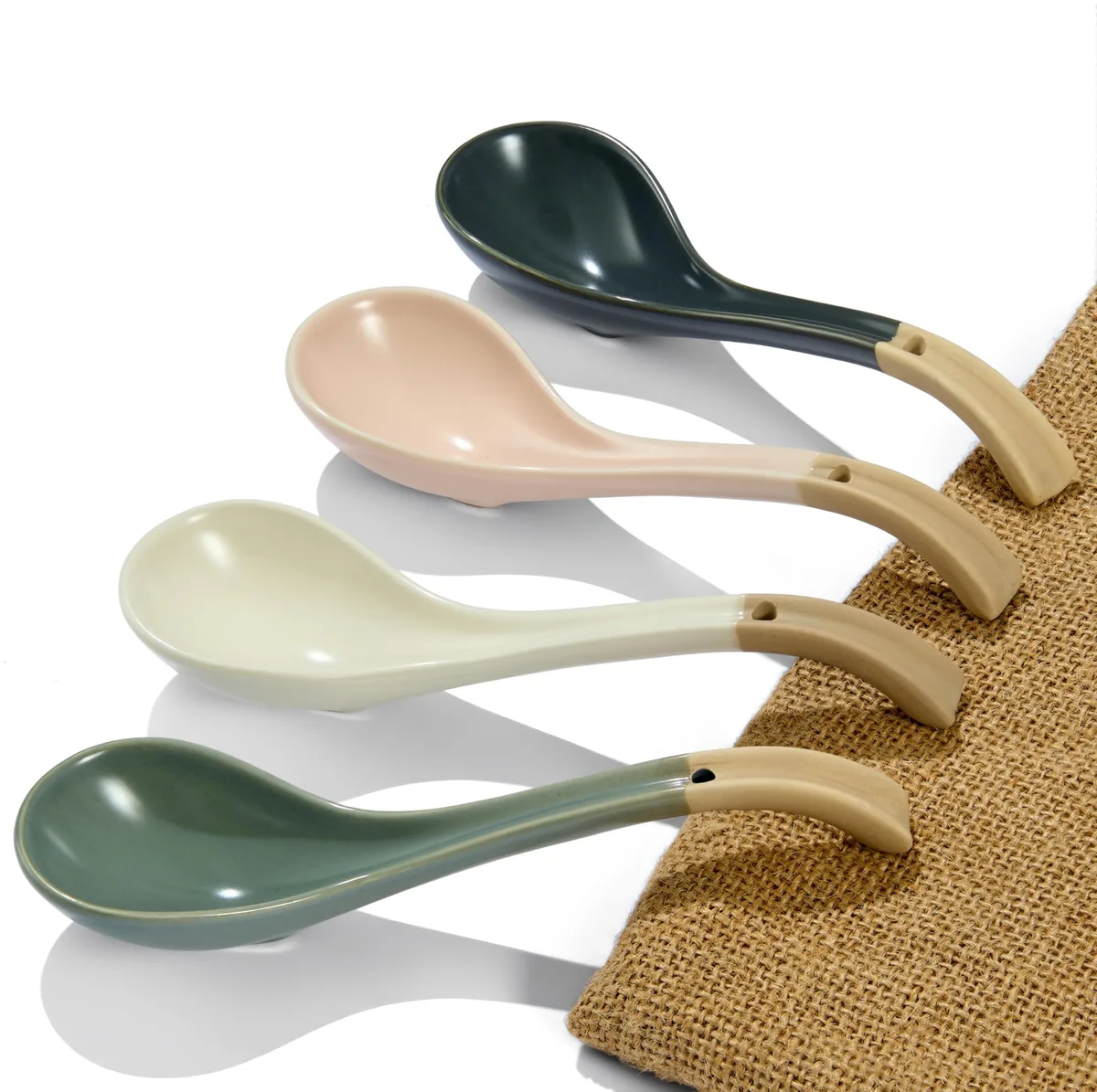 Three white ceramic soup spoons with long curved handles and flat non-slip bases