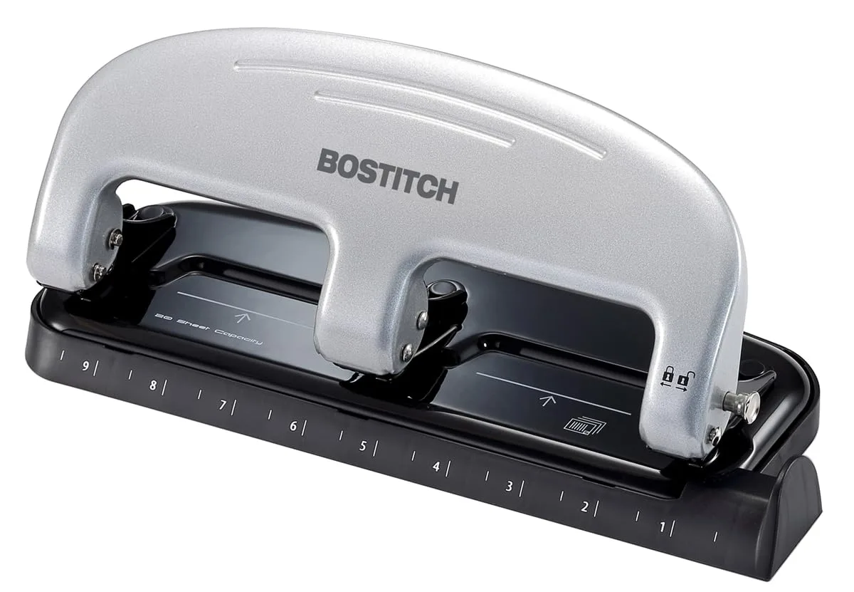 Silver three-hole punch with curved handle, metal body, paper guide, ruler and flip-open chip tray
