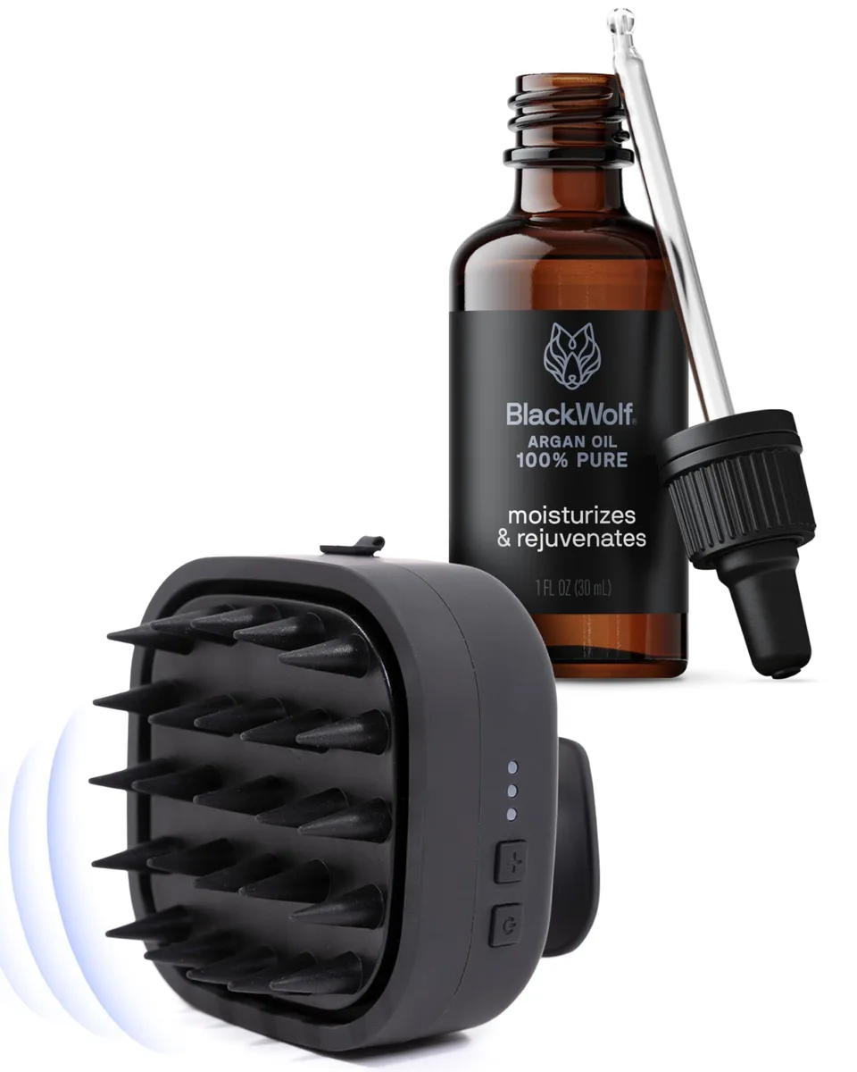 Black handheld scalp massager with silicone bristles and a small argan oil bottle